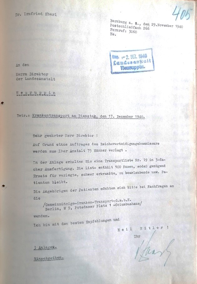 Das Foto zeigt ein Dokument aus der Zeit des Nationalsozialismus. Es handelt sich um ein Schreiben von Dr. Irmfried Eberl, datiert auf den 29. November 1940, gerichtet an den Direktor der Landesanstalt Neuruppin. Der Text erwähnt einen Krankentransport von 15 Männern aufgrund eines Auftrags des Reichsverteidigungskommissars. Es wird auf eine Transportliste Nr. 19 mit 100 Namen verwiesen und es gibt Anweisungen für Rückfragen zur Gemeinnützige Krankentransport GmbH in Berlin.